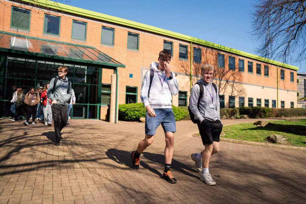 Students walking out of the main entrance in the sunshine