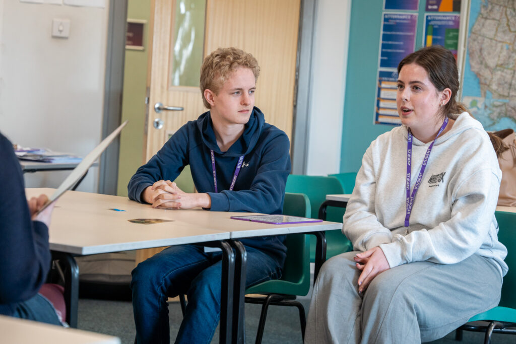 Two students talking with a member of staff across a table