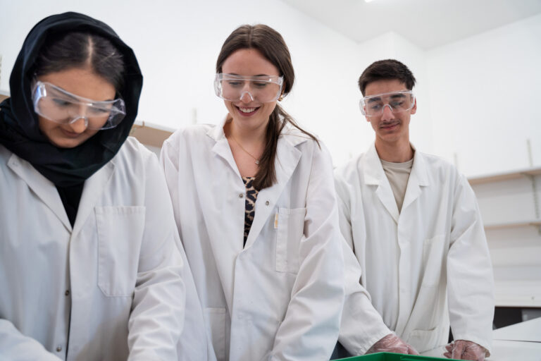 Three students smiling during a biology practical