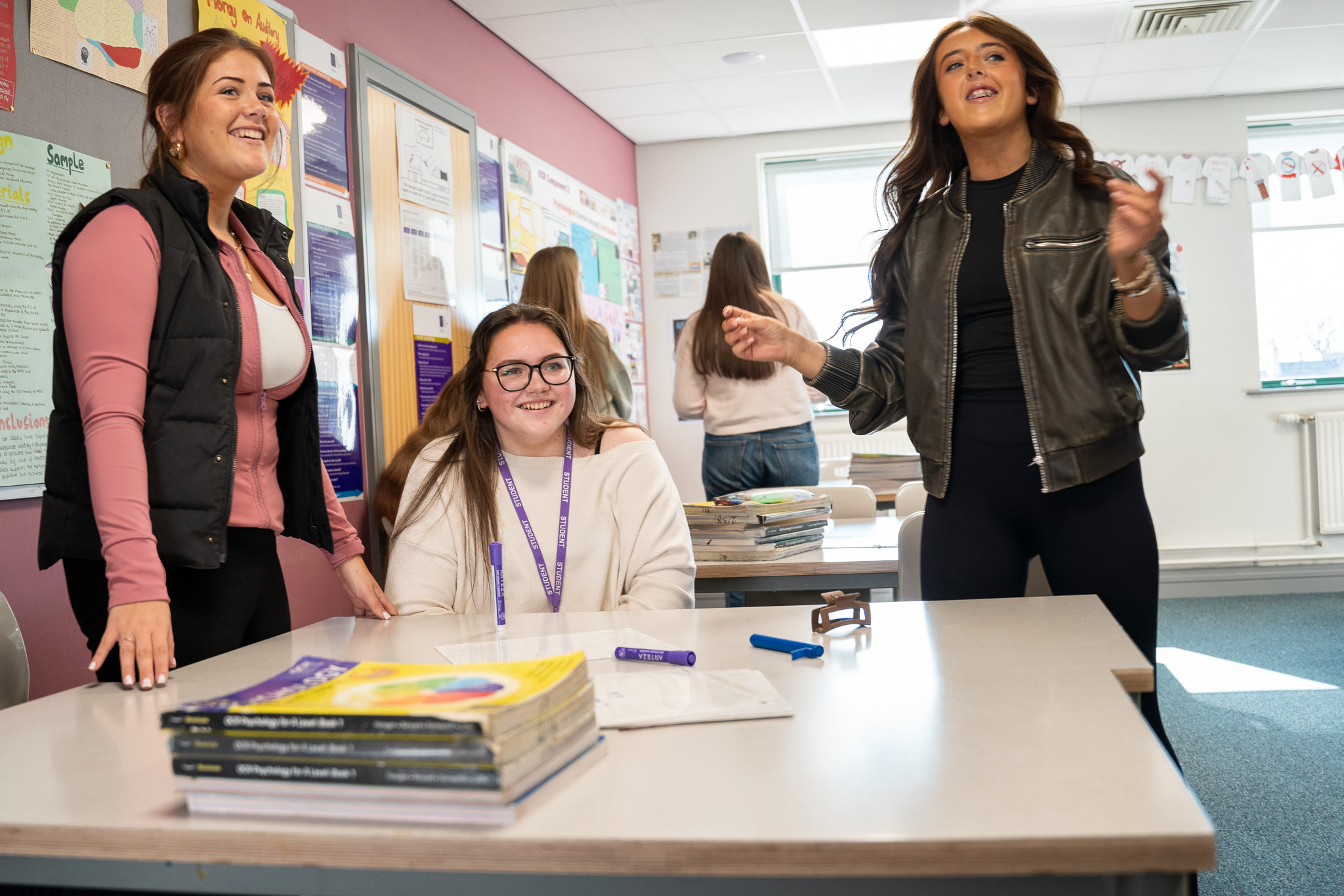 A teacher and two students laughing together in class