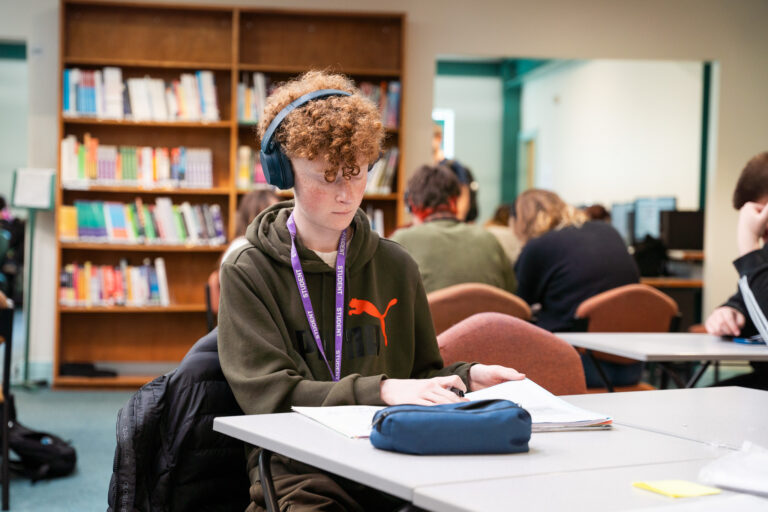 A student reading at a desk in the library