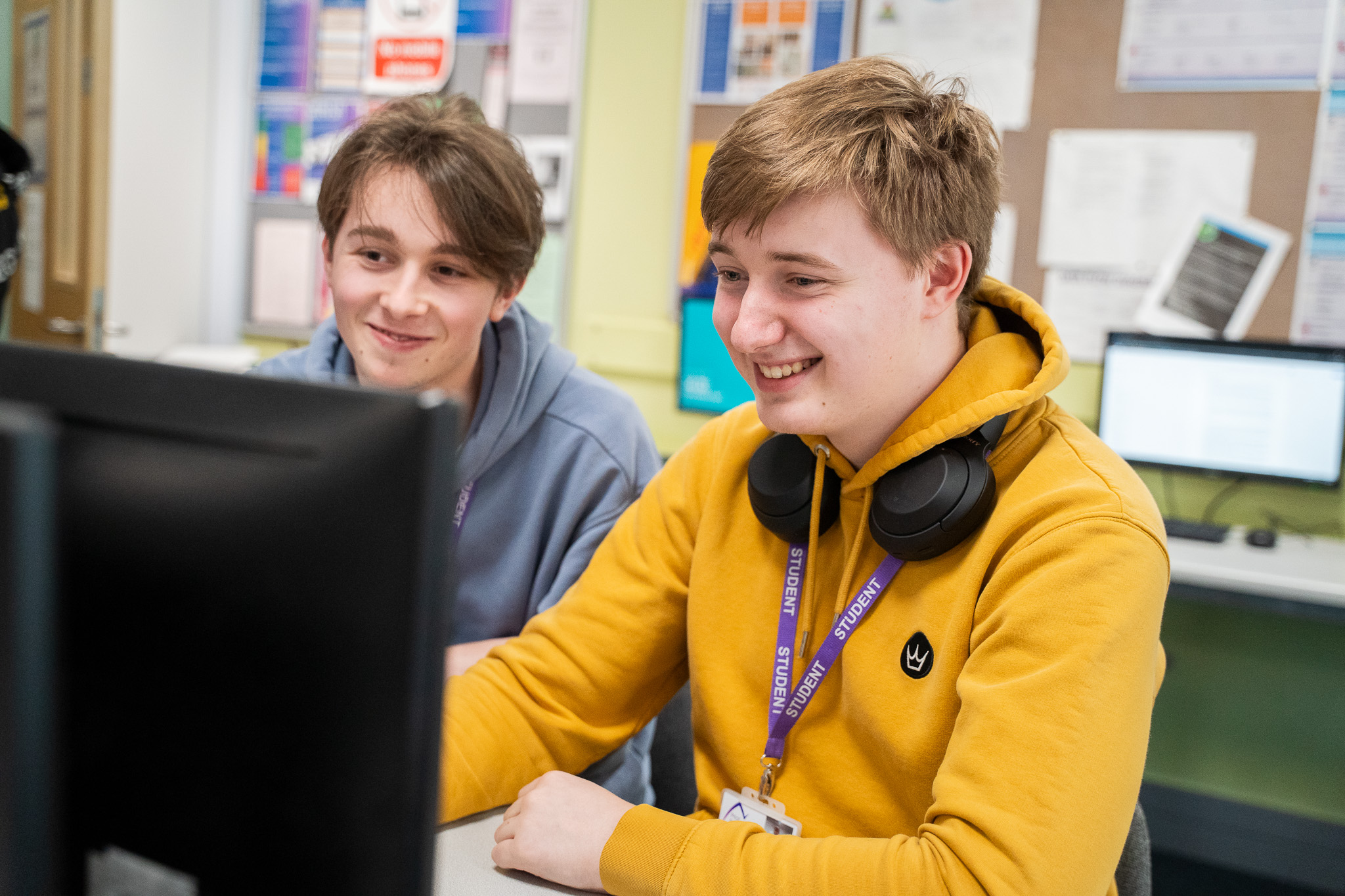 Two students smile at a computer screen in a classroom, Prior Pursglove College.