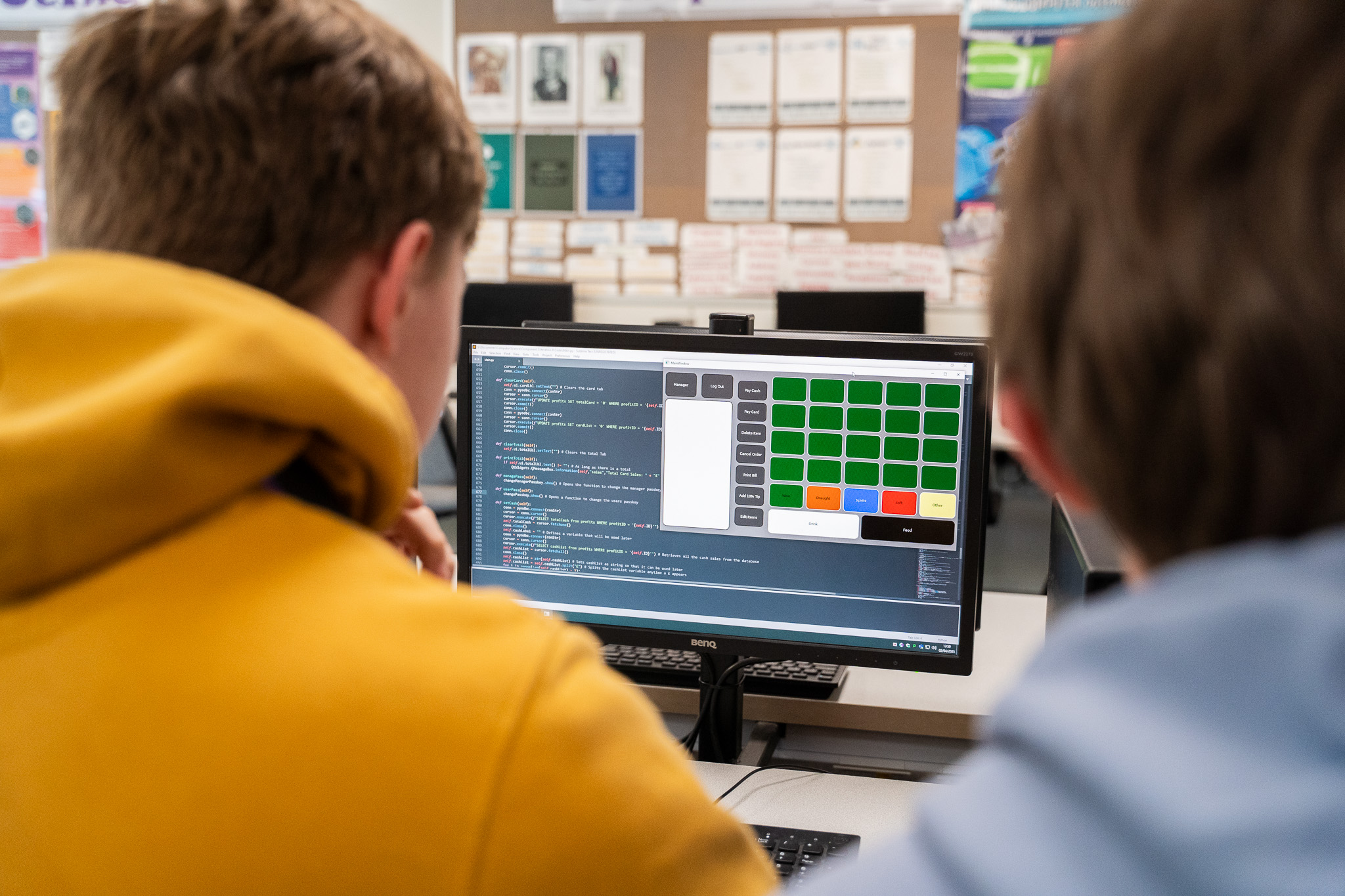Two students looking at code on a screen