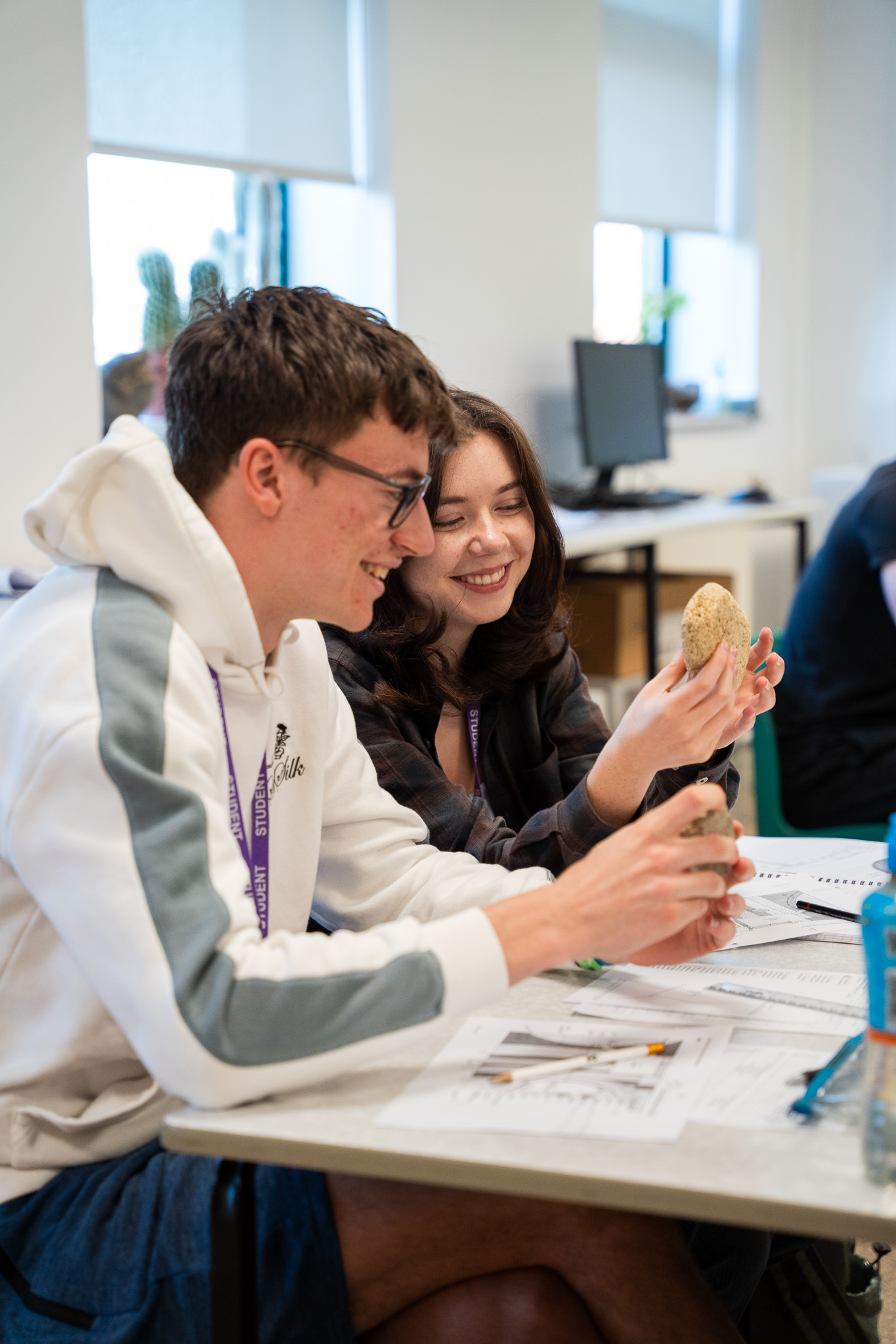 Two students laughing over a rock sample