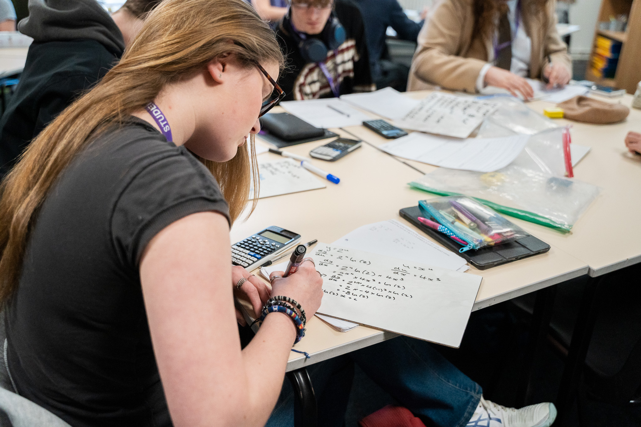A student working through maths problems with a calculator in a classroom at Prior Pursglove College
