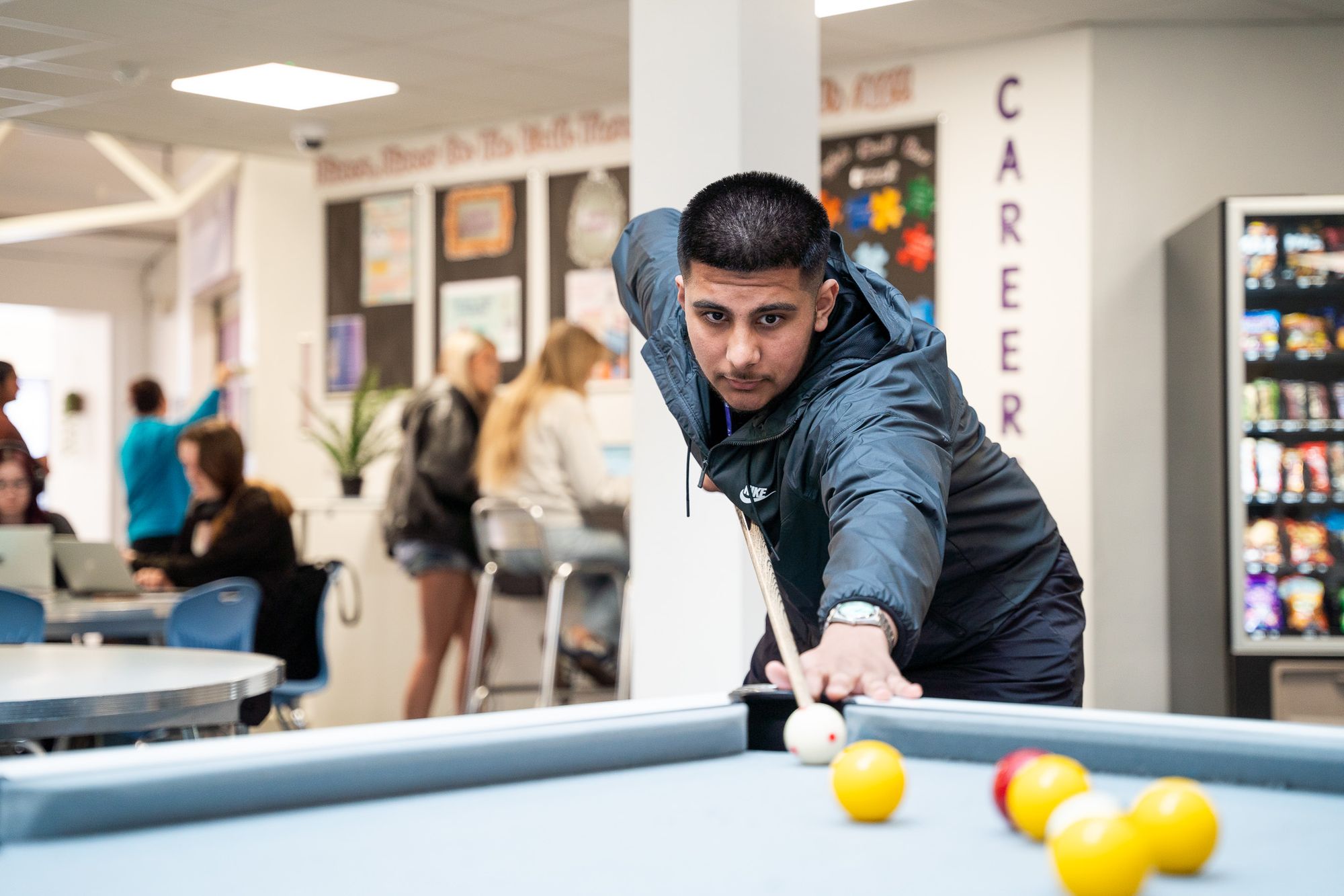 A student taking a shot at the pool table in the common room