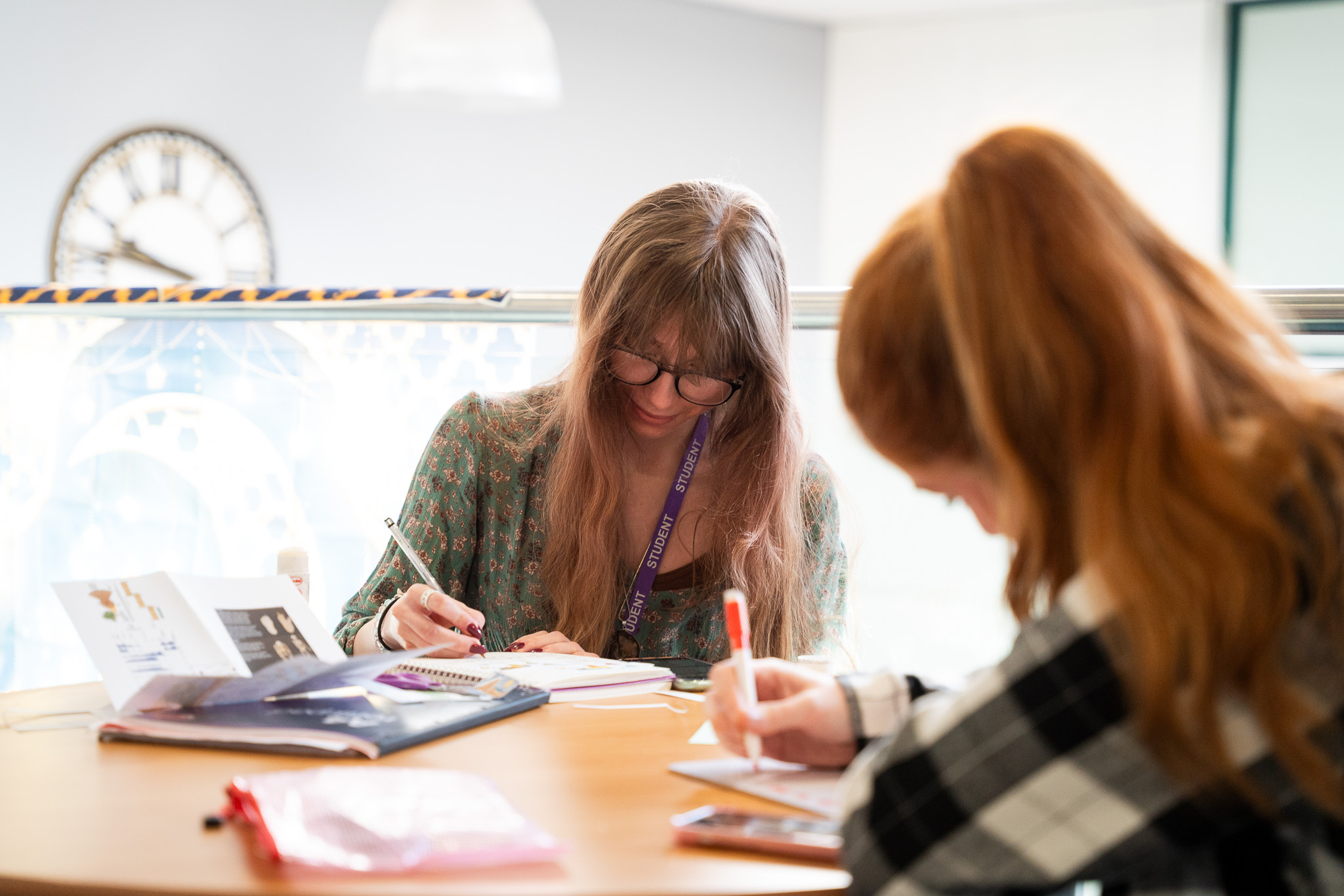 Two students studying and taking notes at a classroom table