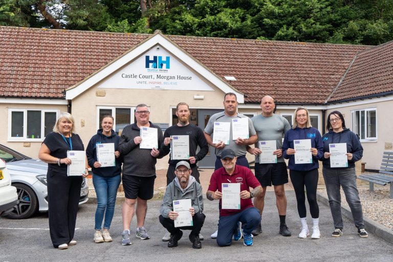 A group of veterans and staff holding certificates outside Castle Court, Morgan House