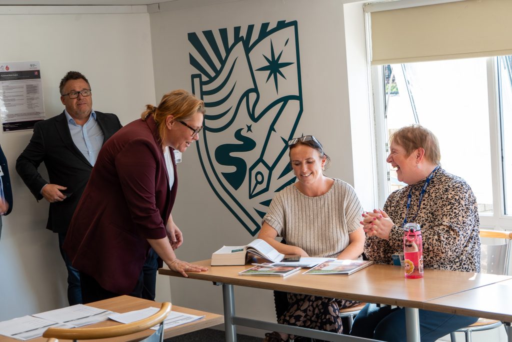 Anna Turley MP leans in to talk with two adult learners at a table in the adult learning classroom