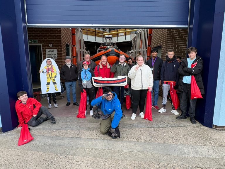Skills for Employment students and staff outside the RNLI lifeboat station in Redcar, holding litter picking bags