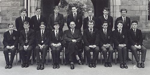 Mr Cooper and a class of students in blazers in two rows in front of the Waterhouse arch, 1963.