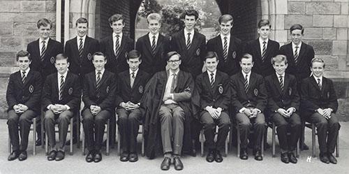 Mr Sanderson and a class of students in blazers in two rows in front of the Waterhouse arch, 1963.
