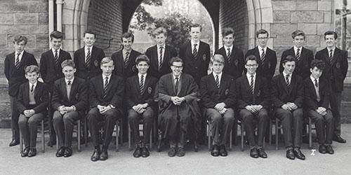 Mr Smythe and a class of students in blazers in two rows in front of the Waterhouse arch, 1963.