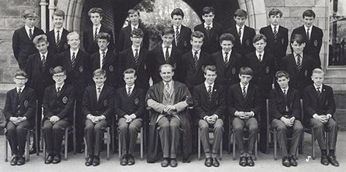 Mr Jackson and a class of students in blazers in three rows in front of the Waterhouse arch, 1963.