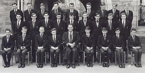 Mr W. N. Thompson and a class of students in blazers in three rows in front of the Waterhouse arch, 1963.