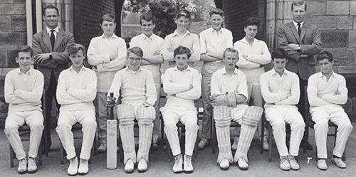 The 1963 cricket team in whites with bats and pads, in two rows in front of the Waterhouse arch, with Mr W. N. Thompson.